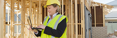 Woman inspector with laptop inspecting a home construction site