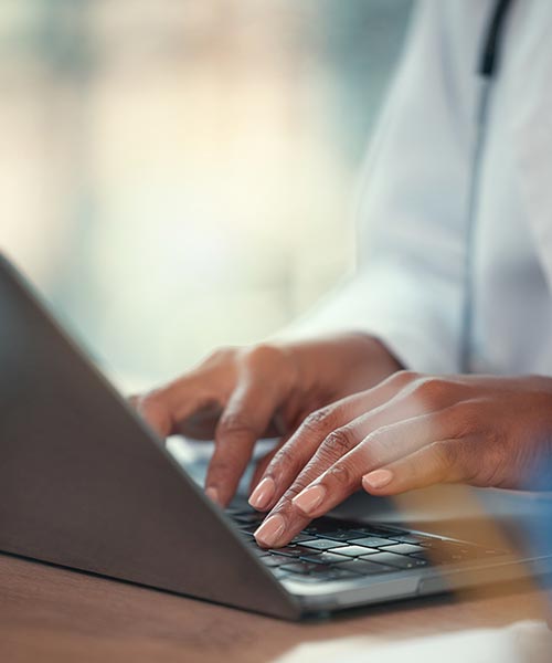 closeup of woman sitting at deskp typing on a laptop