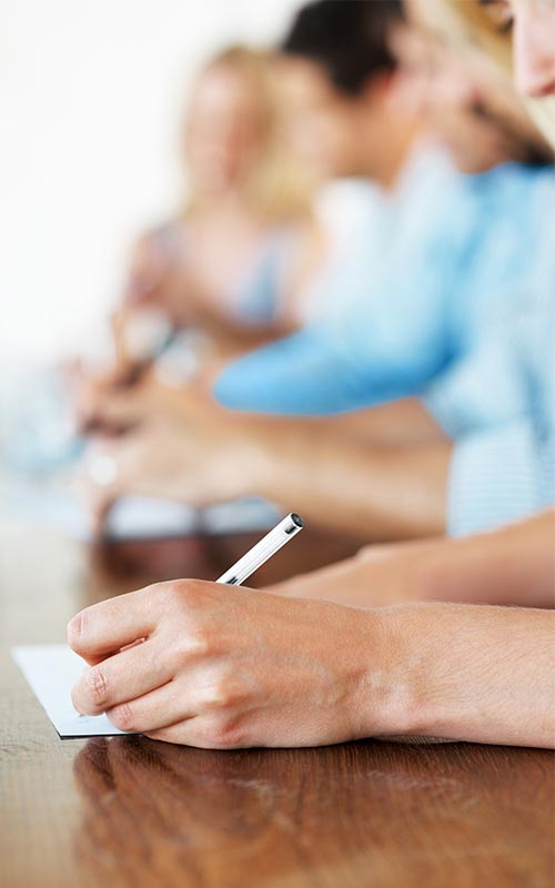 close-up of students in a row taking notes